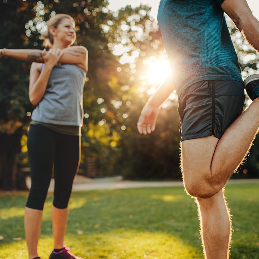 A man and a woman stretching and flexing joints before a jog