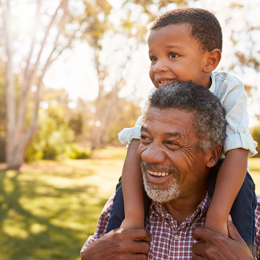 Man smiling and carrying a child on his shoulders