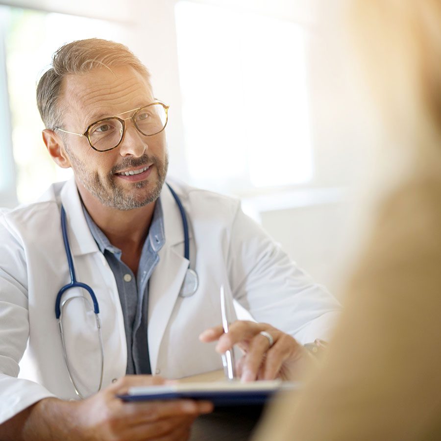 A doctor in a lab coat and stethoscope, talking to a patient